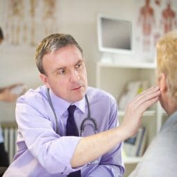 Male doctor looking an a patient's ear