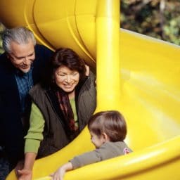 Grandparents watch their grandson go down a slide