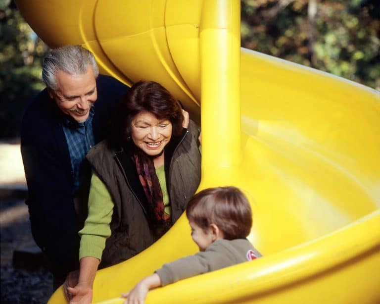 Grandparents watch their grandson go down a slide